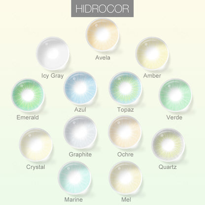 Grid layout of Hidrocor colored contact lenses in various shades with each lens' color name: Avela, Amber, Icy Gray, Azul, Topaz, Verde, Emerald, Graphite, Ochre, Crystal, Marine, Mel, and Quartz, on a soft gradient background.